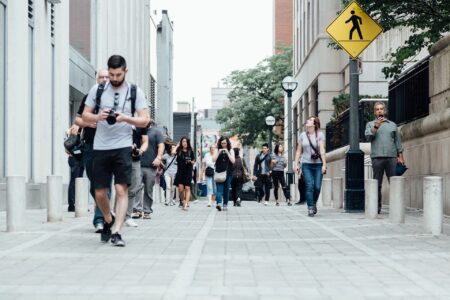 crowd of millennials walking on sidewalk