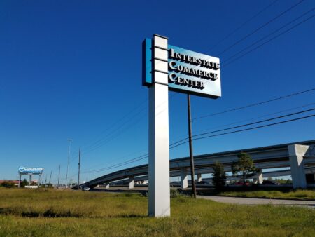 tall metal Houston outdoor signs near busy freeway