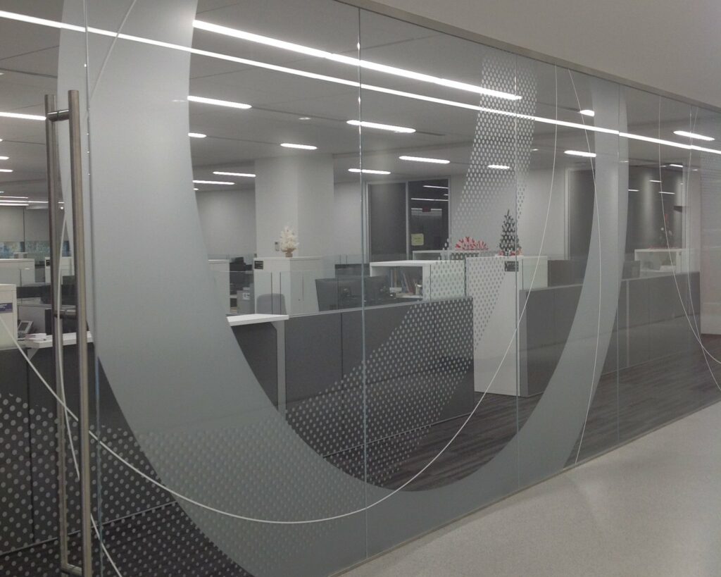 A long office corridor lined with etched-glass environmental and wayfinding graphics, produced by 4D SignWorx in Houston