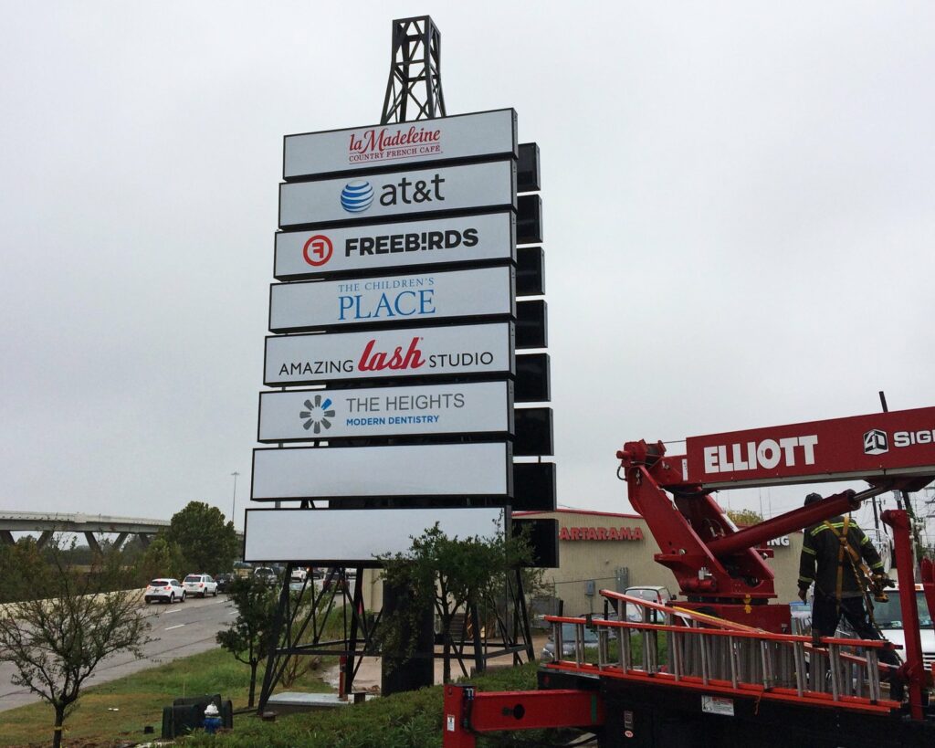 A 4D SignWorx crane crew installing a tall multi-tenant pylon sign in Houston