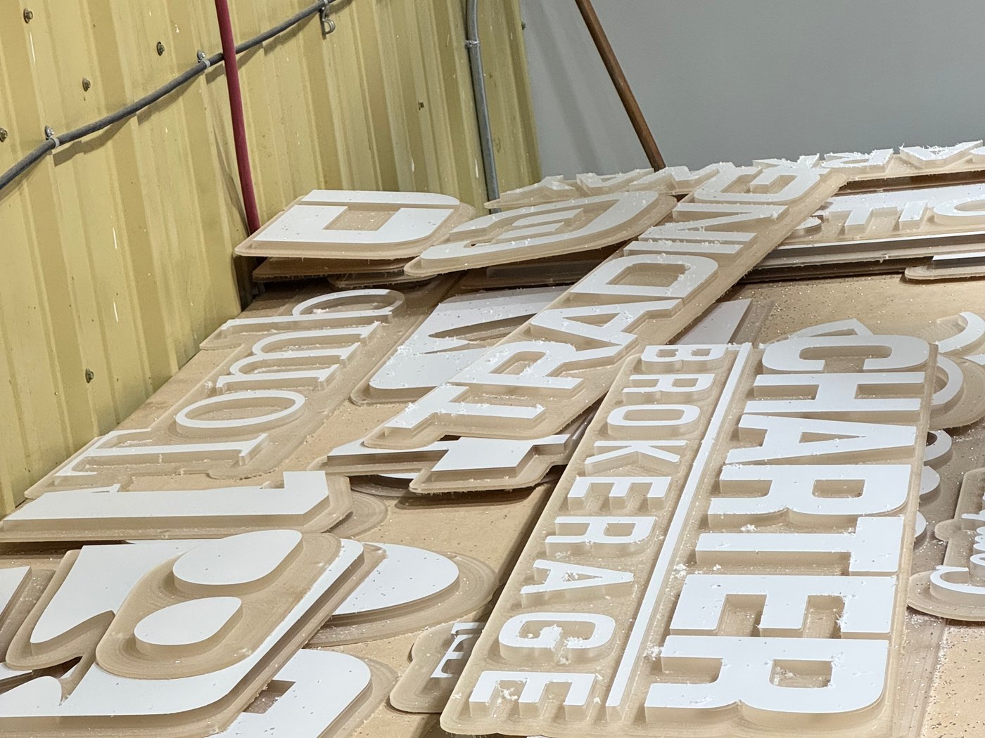Freshly routed dimensional sign letters stacked in the 4D SignWorx Houston shop