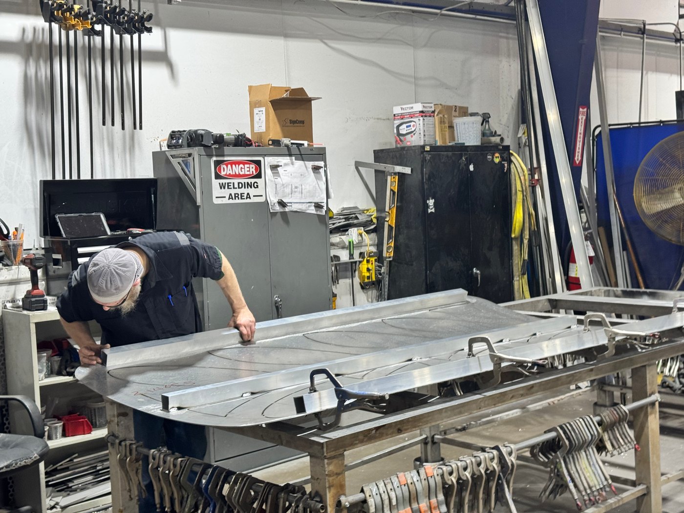 A fabricator finishing an aluminum sign panel in the 4D SignWorx Houston shop