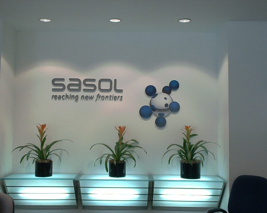 Dimensional brushed-metal lobby letters for Sasol above a lit planter wall, built by 4D SignWorx in Houston